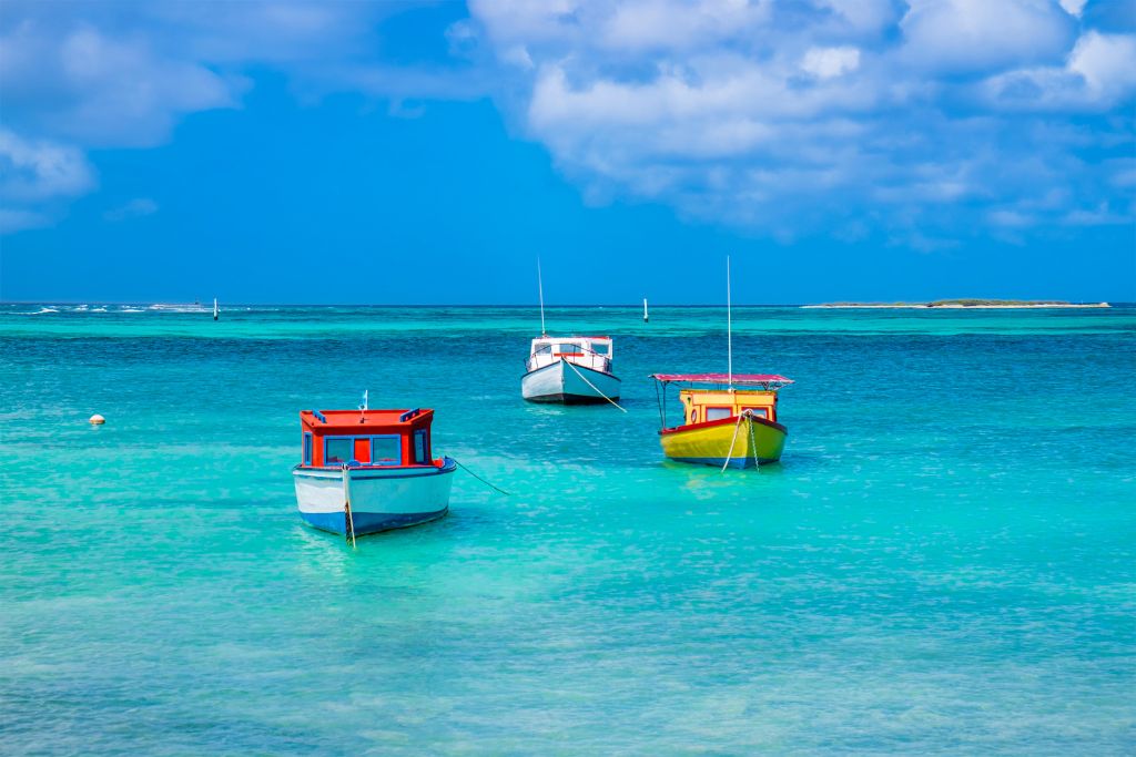 A picture of three boats in the bright blue sea in Aruba.